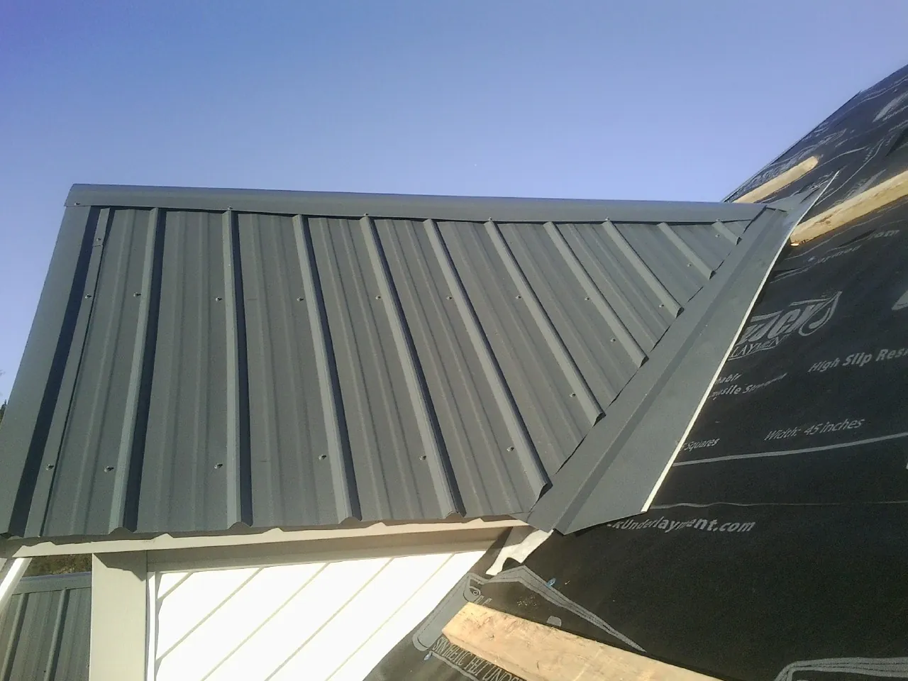 Gray metal roof panels going on over a garage gable in Oak Harbor